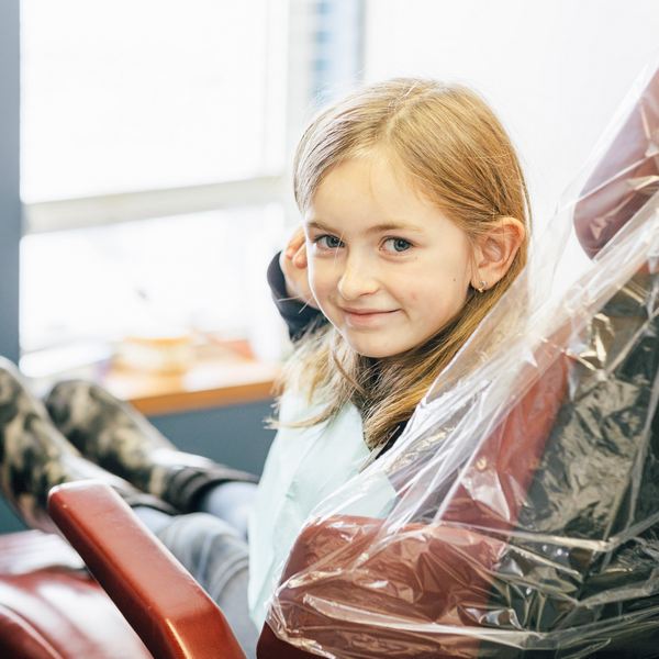 A girl sitting in a dental chair and happily smiling